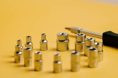 Farklı boyutlarda soketleri ve tornavidayı olan sarı bir yüzeye ayarlı araç