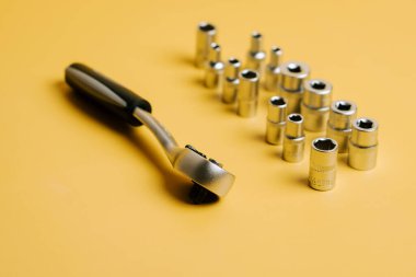 Sarı bir yüzey üzerinde soket anahtarı ve yanında çeşitli soket boyutları olan aletler.