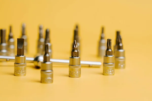 Different types of tool bits on a yellow background with various sizes and shapes visible