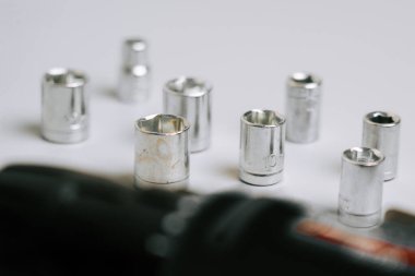 Beyaz bir yüzeye farklı türde metal soketler ve matkap yerleştirilmiştir.