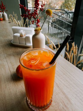 Bir kafenin penceresinin yanındaki ahşap masada buzla ferahlatıcı bir içecek.