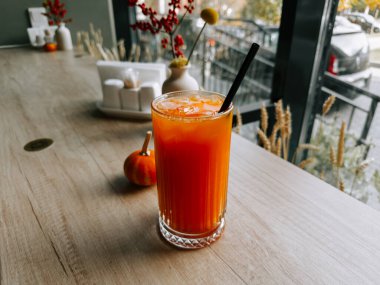 Küçük balkabağı ve çiçeklerle ahşap masada iç öğleden sonra ışığında bir kafede.