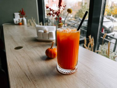 Taze içecek, sonbahar süslemeleri ile birlikte ahşap bir masada servis edilir.