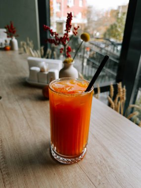 Parlak buzlu içecek, bir kafedeki dekoratif eşyaların yanında, ahşap bir masada, berrak bir bardakta servis edilir.