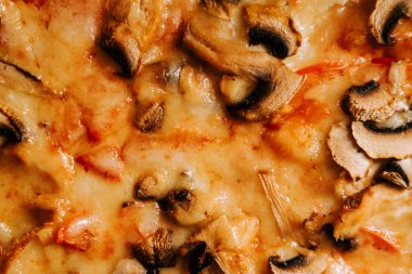 Peynirli, tavuklu ve mantarlı leziz pizza sıradan bir yemek ortamında servis edilir.