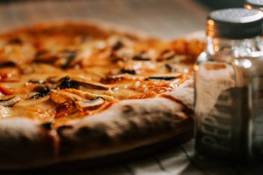 Tahta bir masada peynirli, tavuklu ve mantarlı lezzetli pizza.