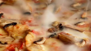 Sıcak bir mutfak ortamında peynirli, tavuklu ve mantarlı lezzetli pizza.