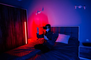 Genç bir kadın akşam saatlerinde yatak odasında sanal gerçekliği keşfediyor.