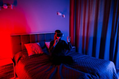 Genç bir kadın evde akşam ışığında sanal gerçekle etkileşime geçiyor.