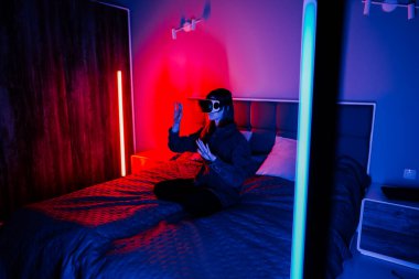 Genç bir kadın geceleri modern bir yatak odasında sanal gerçekliği keşfediyor.