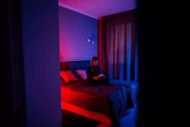 Genç bir kadın akşam saatlerinde yatak odasında sanal gerçeklik gözlüğü kullanıyor.