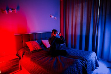 Genç bir kadın gece odasında gözlüklerle sanal dünyaları keşfediyor.