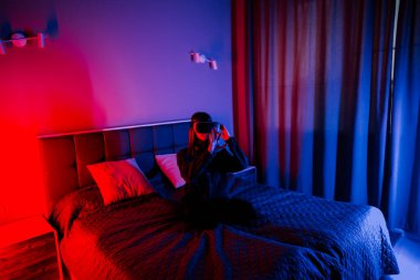 Genç bir kadın akşam saatlerinde yatak odasında sanal gerçeklik deneyiminden hoşlanır.