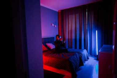 Genç bir kadın gece yatak odasında sanal gerçeklik teknolojisiyle meşgul oluyor.