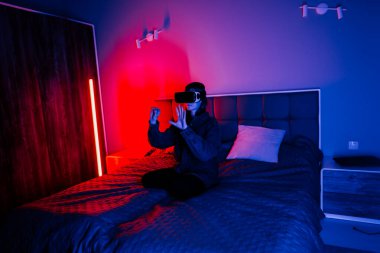 Genç bir kadın, loş bir odada yatarken sanal gerçeklik deneyiminden zevk alır.