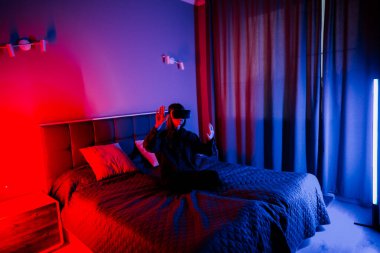 Genç bir kadın gece vakti yatak odasında sanal gerçeklik aktivitesi gerçekleştiriyor.