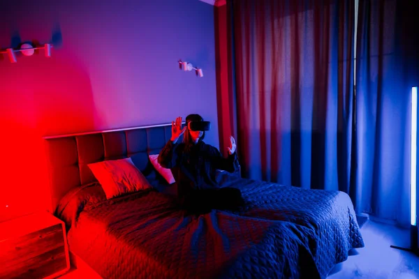 Genç bir kadın gece vakti yatak odasında sanal gerçeklik aktivitesi gerçekleştiriyor.