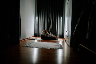 Genç bir kadın sabahleyin spor salonunda evinin zeminine uzanır.