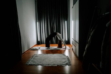 Genç bir kadın akşam saatlerinde evde spor yapıyor.