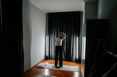 Genç bir kadın iyi ışıklandırılmış bir mekanda spor yapıyor.