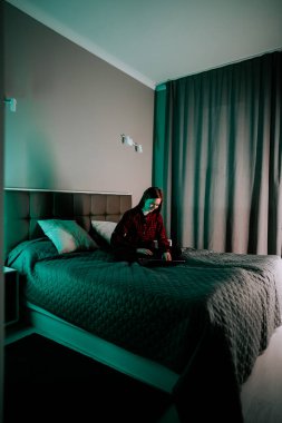 Genç kadın rahat yatak odasında yatarken dizüstü bilgisayarda ders çalışıyor.