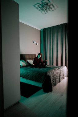 Akşam ışığında evde dizüstü bilgisayarla tek başına ders çalışan genç bir kadın.