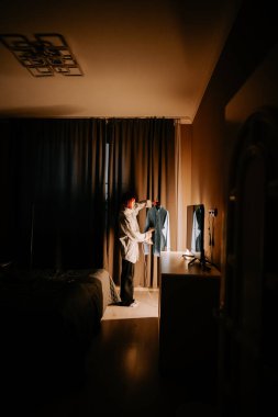 Yatak odasındaki gömleğe buharlı ütü kullanan genç bir kadın.