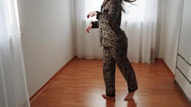 Kadın evinde leopar desenli pijamalarıyla dans ediyor.