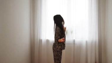 Kadınlar güneşli bir sabahta evde leopar desenli pijamalarıyla dans eder.
