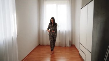 Kadınlar gündüz evde leopar desenli pijamalarıyla dans eder.