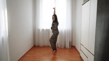 Kadınlar güneşli bir günde evde leopar desenli pijamalarıyla dans eder.