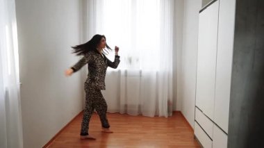 Sabah vakti evde leopar desenli pijamalı dans eden kadın.