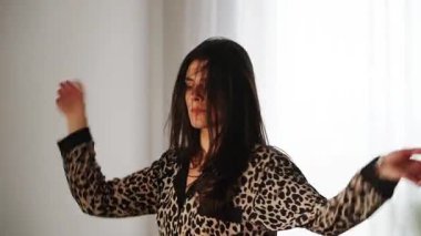 Kadınlar gündüz evde leopar desenli pijamalarıyla dans eder.