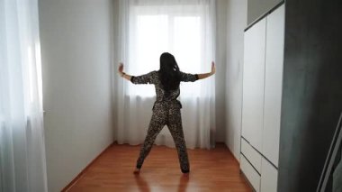 Kadın evde yalnız dans ediyor leopar desenli pijamalarıyla sabah vakti.
