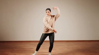 Kadın, dans salonunda akşam antrenmanı sırasında enerji ve odak ile dans ediyor.