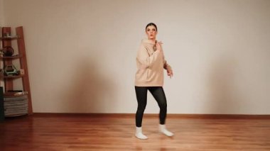 Ahşap zemini olan bir dans salonunda dans eden bir kadın.