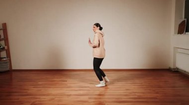 Gündüz antrenmanı sırasında dans salonunda tek başına dans eden kadın.