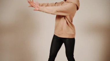 Bir kadın dans salonunda kapüşonlu ve taytlı dans eder.