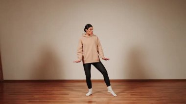 Dans salonunda dans eden bir kadın antrenman sırasında ritim ve hareket gösterir.