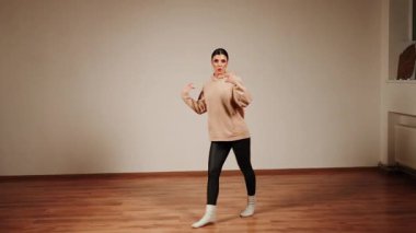 Gündüz dans salonlarında dans eden, hareketlerini ve ifadelerini sergileyen bir kadın.