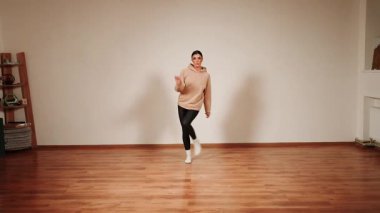 Dans pistinde tek başına dans eden bir kadın. Ahşap zemin ve basit bir zemin.