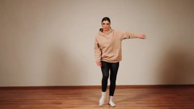 Dans salonunda dans eden kadın, hareketlere ve sıcak ışıkta ifade etmeye odaklanıyor.