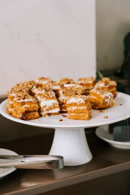Beyaz pasta standında pasta dilimleri. Parlak bir oda ortamında basit bir arka planı var.