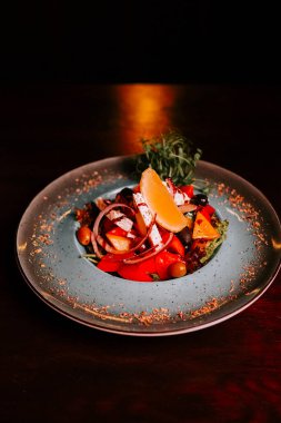 Mavi tabakta garnitürle servis edilen çeşitli sebzelerle taze salata.