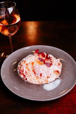 Sıcak bir restoranda bir bardak gül şarabıyla servis edilen lezzetli makarna tabağı.