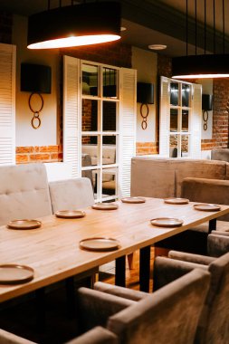 Ahşap masalı yemek alanı ve restoran ortamında misafirler için yumuşak koltuklar.