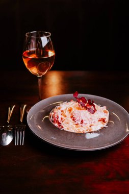 Bir tabak makarna ve karanlık bir masada bir bardak şarapla güzel bir yemek.