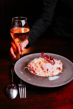 Akşam bir restoranda yemek masasında bir bardak şarapla yemeğin tadını çıkarıyorum.