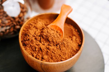 Kakao tozu ahşap bir kasede, mutfak masasında bir kaşıkla.