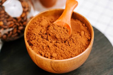 Mutfak masasında bir kepçe kakao tozu ve kahve çekirdekleri.